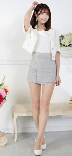 Woman in a white jacket and plaid skirt posing indoors