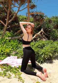 Woman in black sports bra and leggings posing on a sandy beach