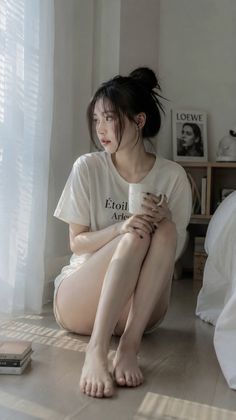 Woman in a white t-shirt and shorts sitting on the floor by a window