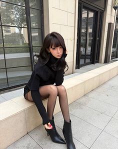 Woman in a black turtleneck and tights sitting outdoors