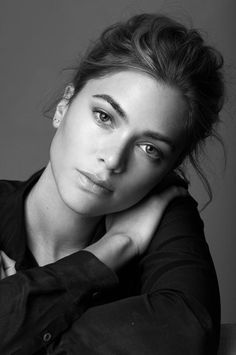Woman with a messy bun in a black shirt, looking directly at the camera
