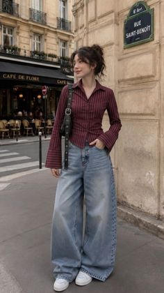 Woman in a striped shirt and wide leg jeans on a street in front of a cafe
