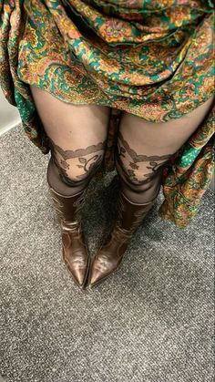 Person wearing a paisley dress, lace stockings, and brown boots indoors
