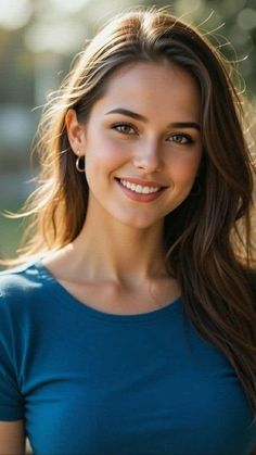 Woman with long brown hair smiling in a blue shirt outdoors