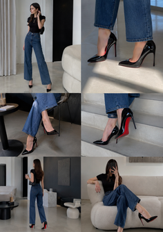 Woman in blue jeans and black top posing in a modern indoor setting