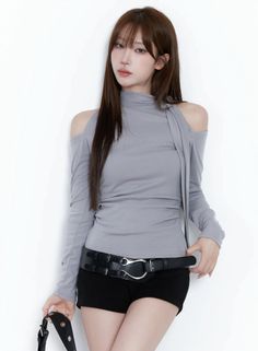 Woman with long brown hair wearing an off-shoulder top and black shorts