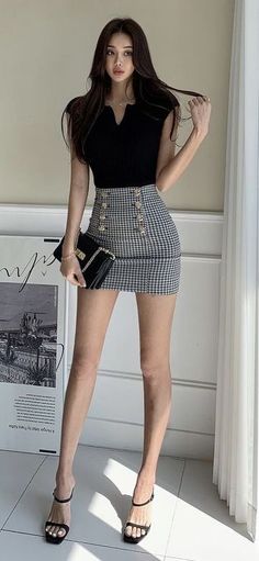 Woman in a black top and houndstooth mini skirt holding a handbag indoors