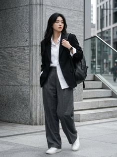 Woman in a black blazer and wide leg pants walking outdoors