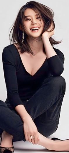 Woman with short hair and a black top, smiling in a studio shot