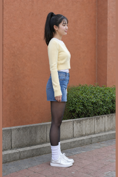 Woman in a yellow cardigan and denim shorts with black tights and white socks