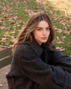 Woman with long hair and blue eyes sitting on a park bench in autumn