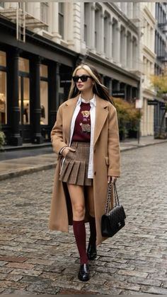 Woman in a long coat and plaid skirt walking on a cobblestone street