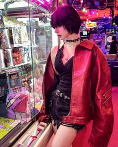 Person in a red leather jacket and black lace top at an arcade