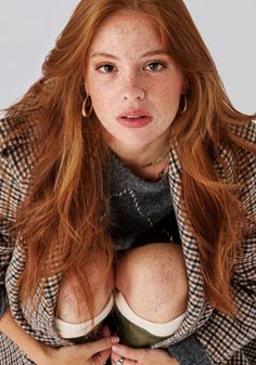 Woman with red hair and freckles wearing a plaid jacket and nose ring