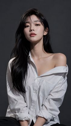 Woman with long black hair wearing an unbuttoned white shirt in a studio
