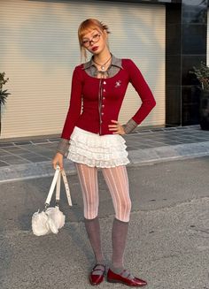 Woman in a red top, white ruffled skirt, and patterned tights posing outdoors