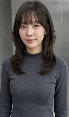 Woman with dark hair and bangs wearing a gray mock neck long sleeve top
