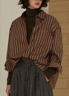 Person in a striped shirt and turtleneck with short hair and glasses