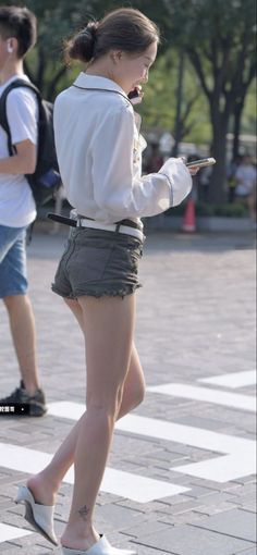 Woman in short shorts and a white shirt walking on a street