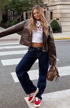 Woman in a brown leather jacket and wide leg jeans on a crosswalk
