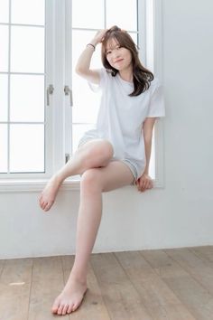 Woman in a white t-shirt and shorts sitting on a window sill