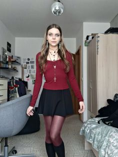 Woman in a red top, black skirt, and red tights standing in a room