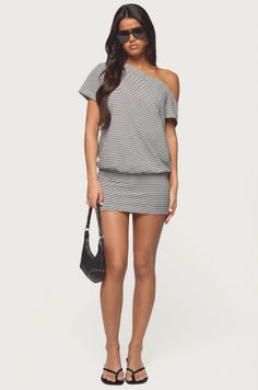 Woman in a striped off-shoulder mini dress and sunglasses holding a black handbag