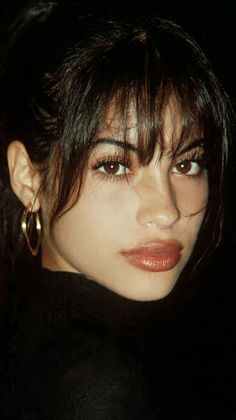 Woman with dark hair and hoop earrings wearing a black top