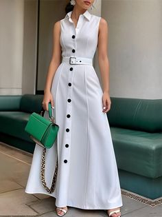 Woman in a white sleeveless dress with a green handbag standing outdoors