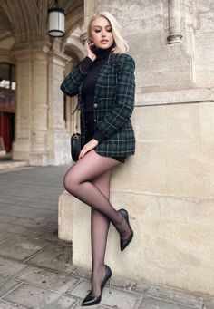 Woman in a plaid blazer and black tights posing outdoors