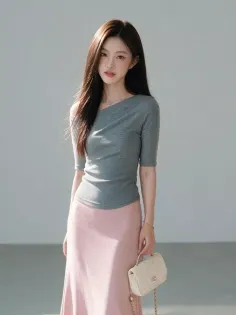 Woman with long dark hair wearing a gray top and pink skirt, holding a small handbag