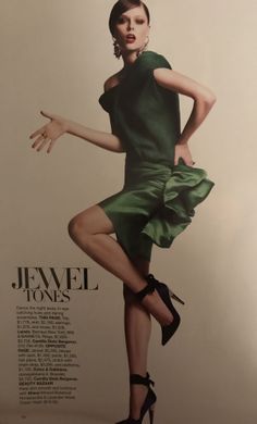 Woman in a green dress and high heels posing in a studio