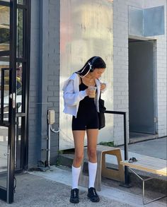 Woman in a black romper and white jacket with headphones outdoors