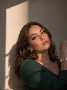 Woman with short brown hair and green eyes in a green sweater with soft lighting