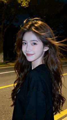 Woman with long dark hair smiling at night outdoors
