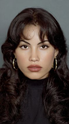 Woman with long dark hair and hoop earrings in a studio portrait