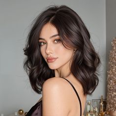 Woman with dark wavy hair looking over her shoulder in a dimly lit room