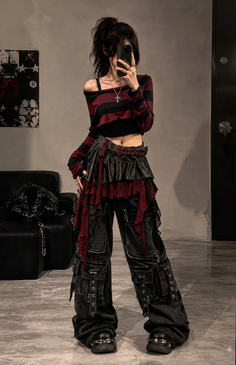 Person in gothic-style clothing with a cropped top and cargo pants indoors