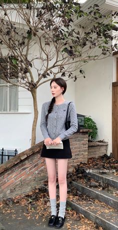 Woman with a braid wearing a gray cardigan and black mini skirt outdoors