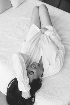 Woman in a white shirt lying on a bed with exposed legs