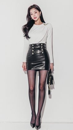 Woman in a white top and black leather skirt with a handbag