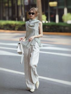 Woman in a sleeveless top and wide-leg pants walking on a street