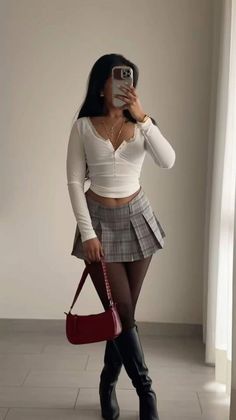 Woman in a plaid skirt and crop top taking a mirror selfie