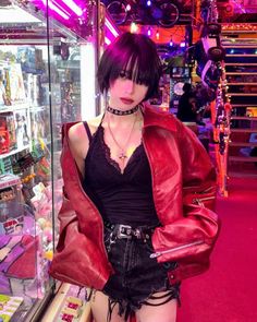 Woman in a red leather jacket and black lace top in a neon-lit indoor setting