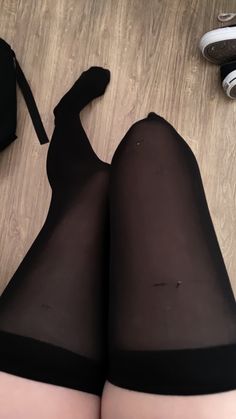 Person wearing black thigh-high stockings on a wooden floor