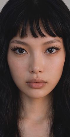 Close up portrait of a woman with black hair and bangs looking directly at the camera