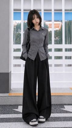 Woman with short hair wearing a striped shirt and wide leg pants outdoors