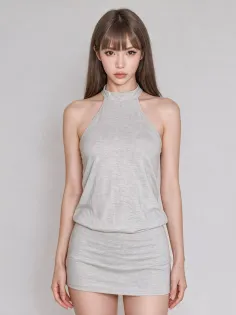 Woman with long light brown hair wearing a light gray halter mini dress