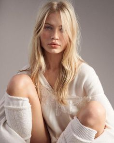 Blonde woman with freckles wearing a white top with lace trim and knee-high socks