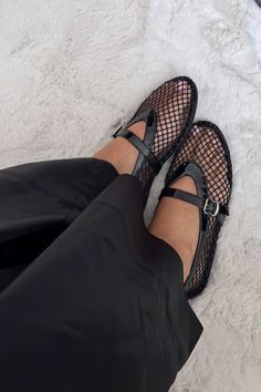 Person wearing black mesh Mary Jane shoes and black pants on a white furry rug